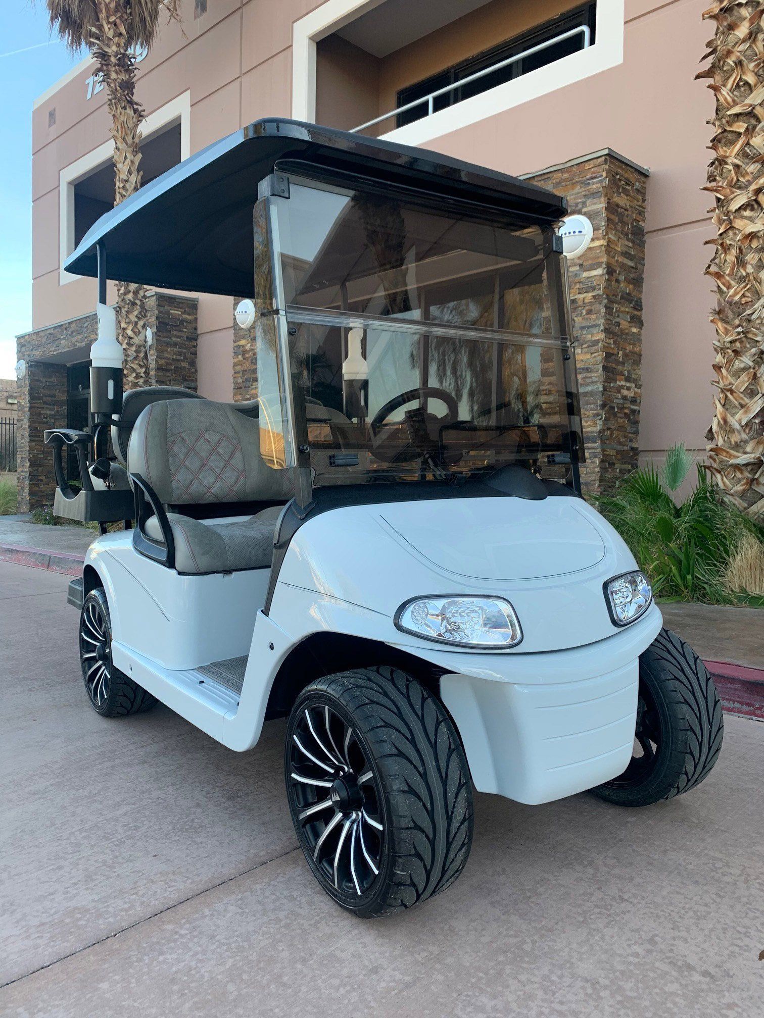 A white golf cart is parked in front of a building.