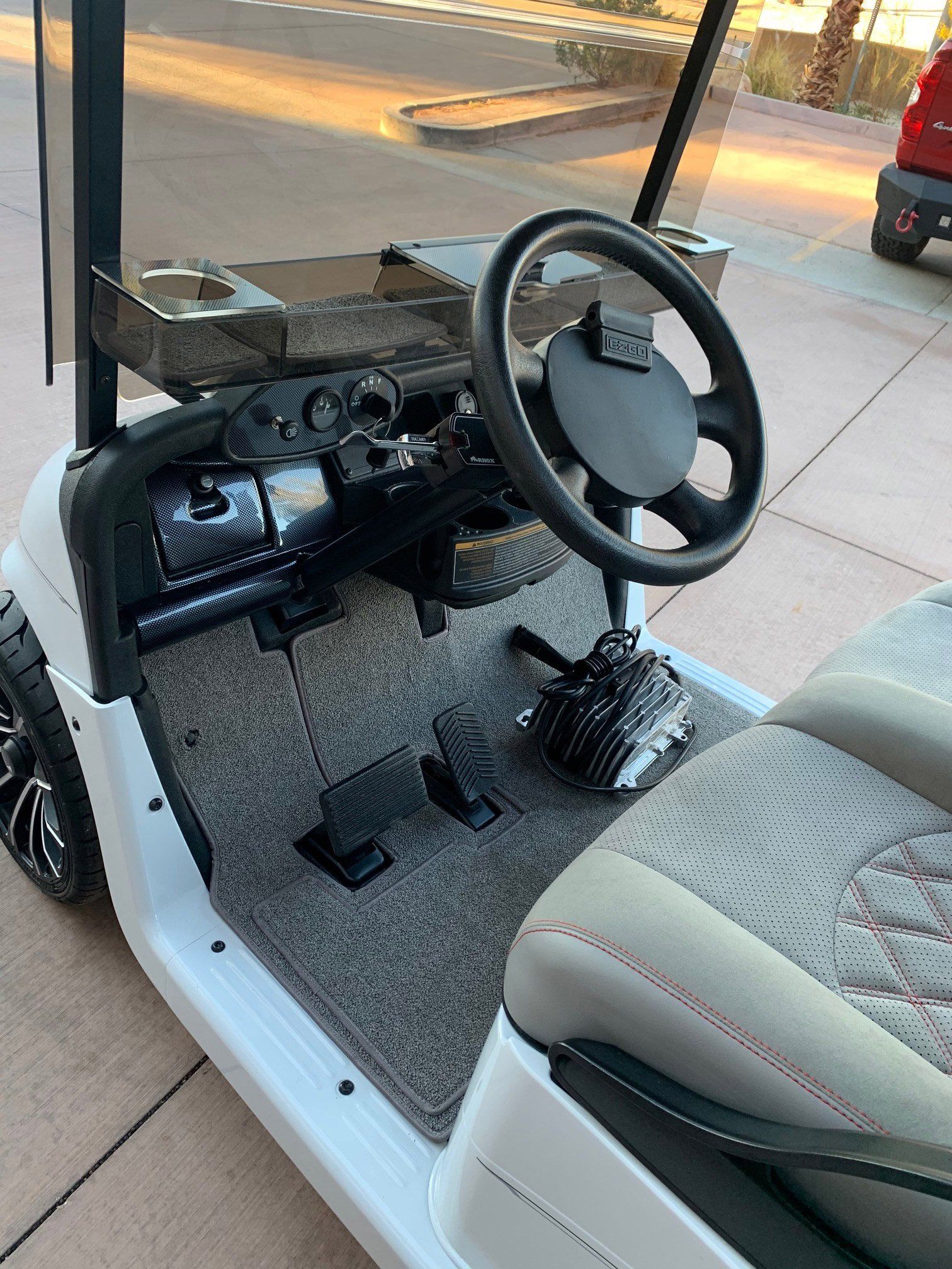 The inside of a golf cart with a steering wheel and seats.