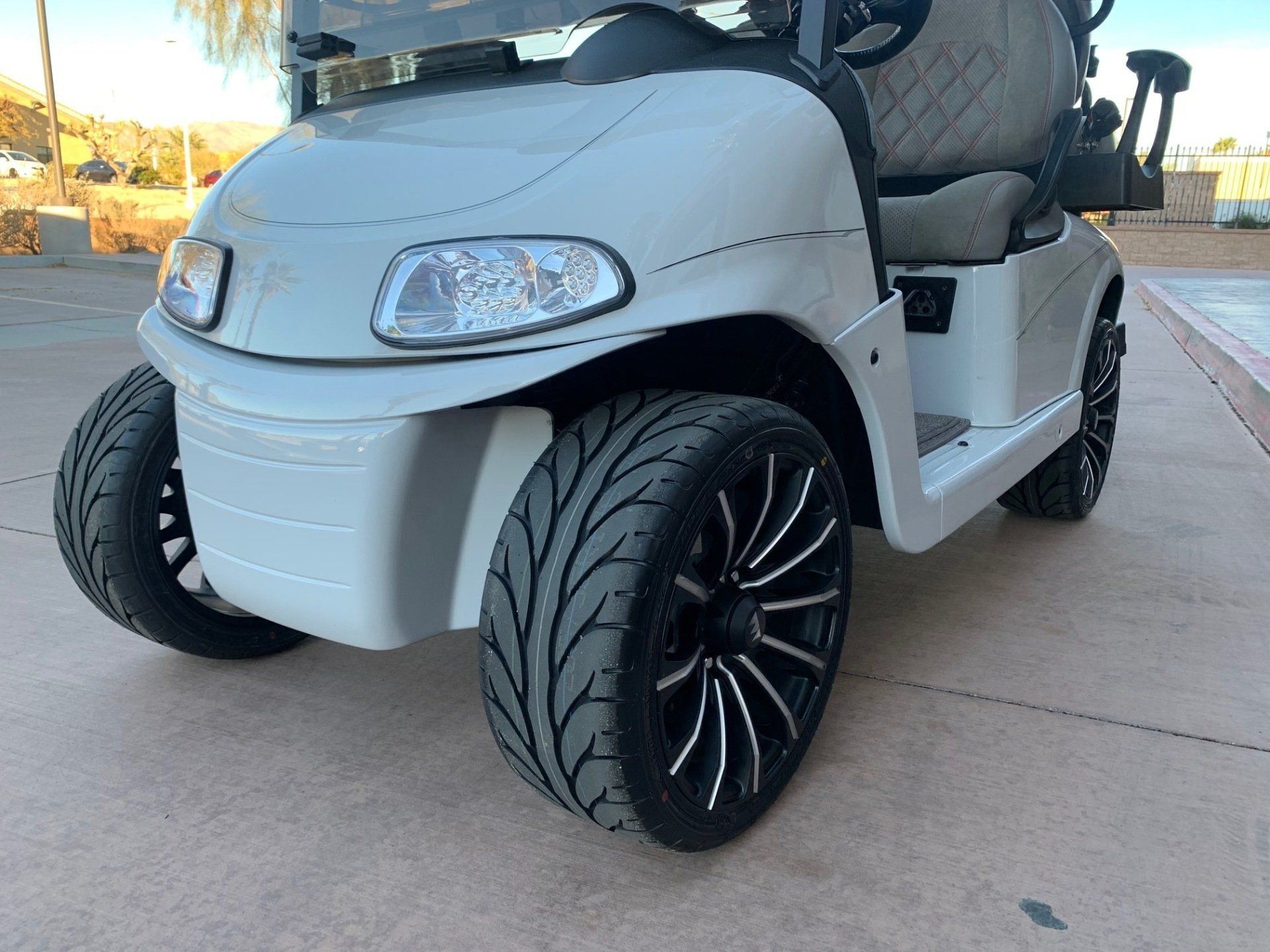 A white golf cart is parked on the side of the road.