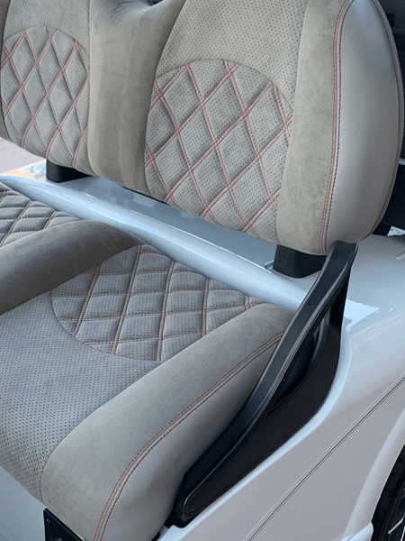 A close up of a golf cart seat with a red stitching
