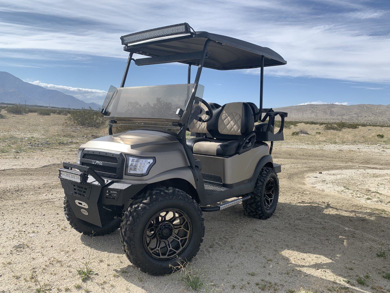 A golf cart is parked in the middle of a dirt field.