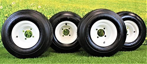 Four tires and wheels are sitting on top of a lush green field.