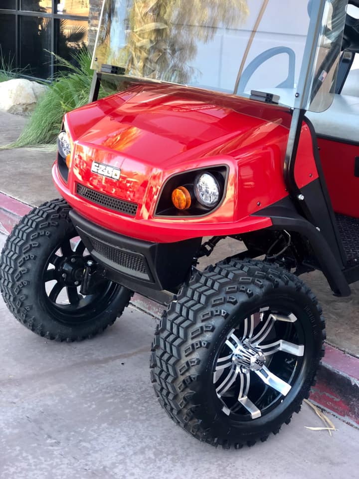 A red golf cart is parked on the side of the road.