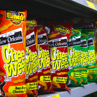 Several bags of chee chee cheese are lined up on a shelf