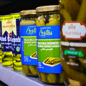 Several jars of pickled cucumbers are lined up on a shelf