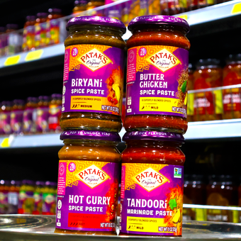 Four jars of sauce are stacked on top of each other in a store.
