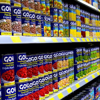 A grocery store shelf filled with cans of goya