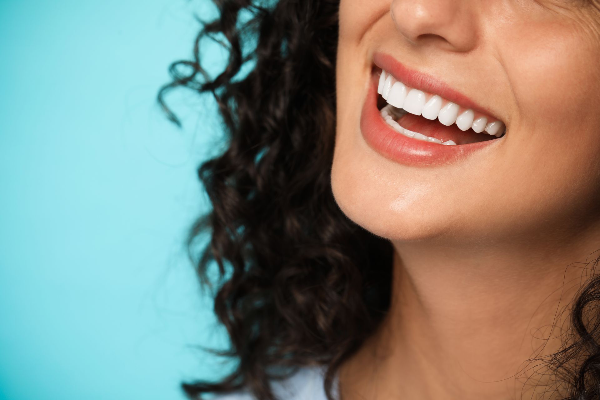 Close-up of a woman smiling with bright, even white teeth after cosmetic dental treatment Close-up of a woman smiling with bright, even white teeth after cosmetic dental treatment