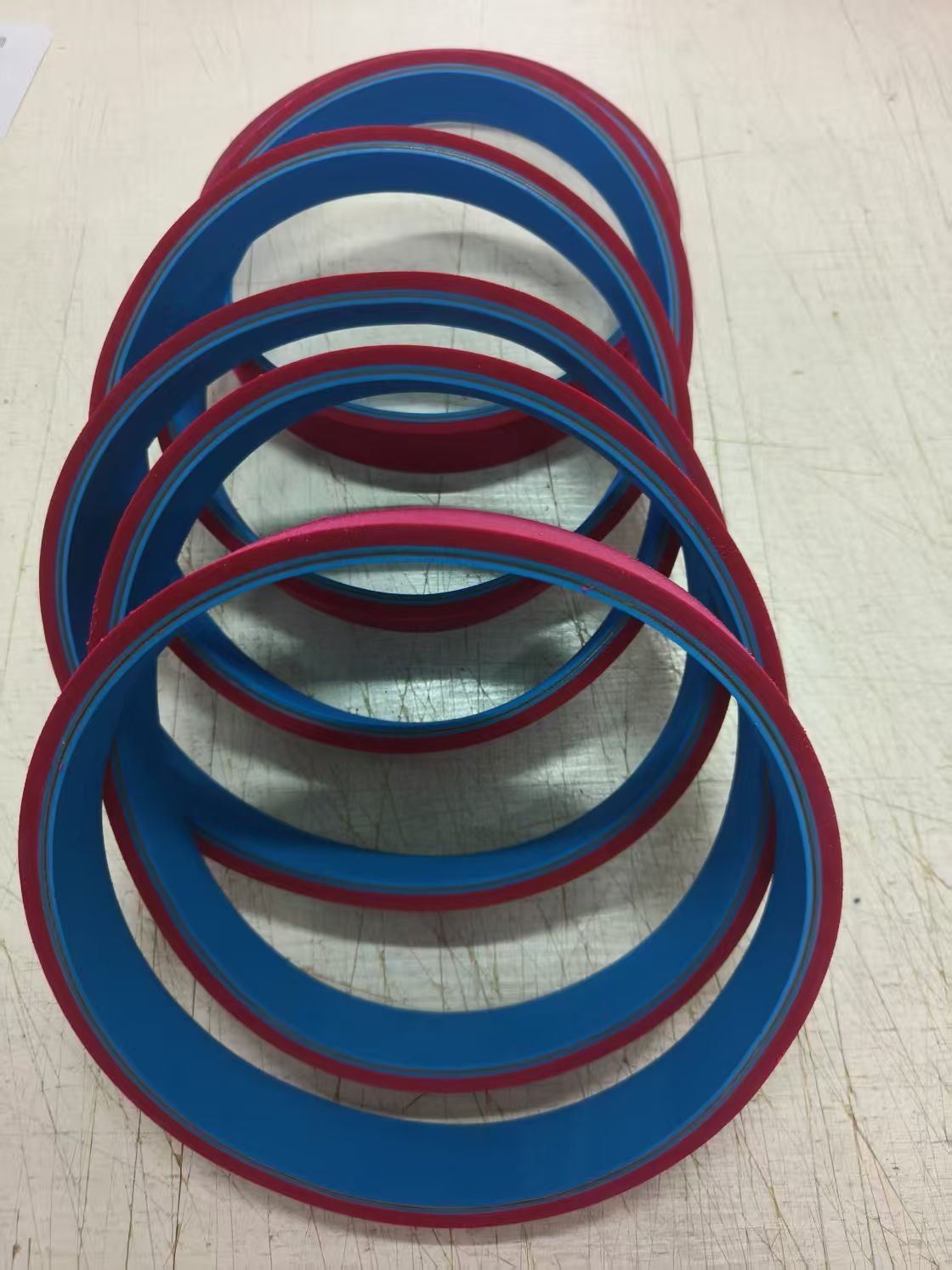 Apilamiento de anillos circulares azules y rojos sobre una mesa blanca.