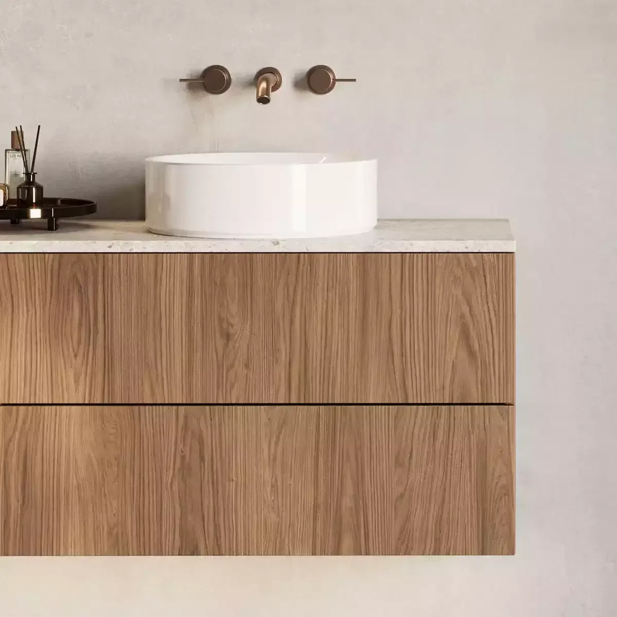 Moderne badkamerkast met houten lades, witte opbouwspoelbak en bronzen wandkraan op een lichte muur.