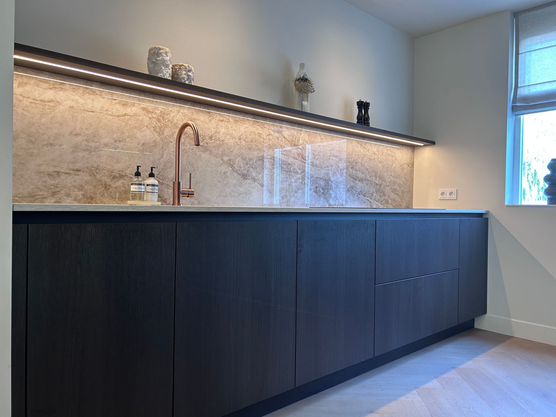 Moderne keuken met wit kookeiland, zwart aanrechtblad en ingebouwde apparatuur in een minimalistische ruimte.