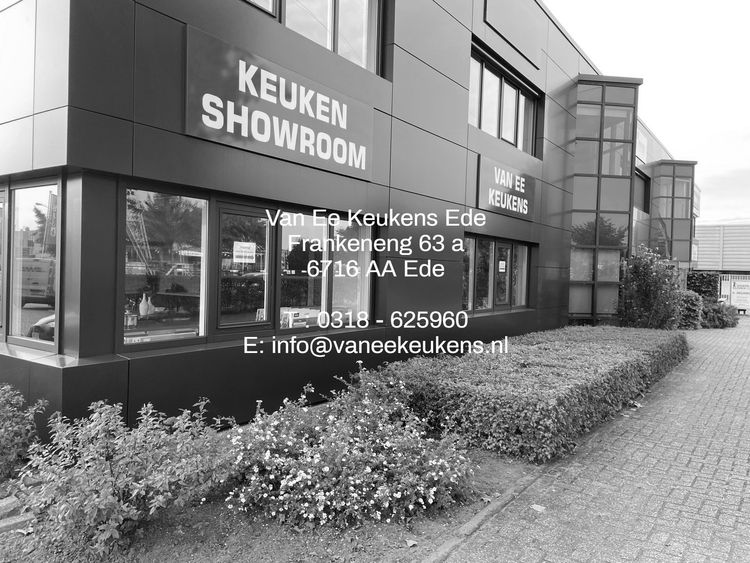 Onze showroom De buitenkant van de Keuken Showroom-winkelpui met grote reclameborden en beplanting ervoor.