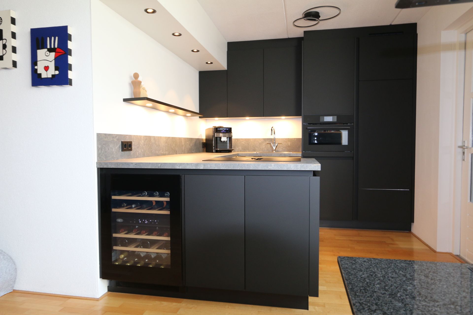 Moderne keuken met wit kookeiland, zwart aanrechtblad en ingebouwde apparatuur in een minimalistische ruimte.