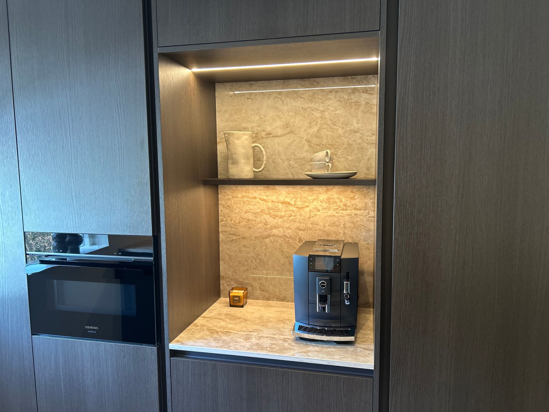 Modern keukeneiland met zwart aanrechtblad in een lichte ruimte naast een glazen deur.