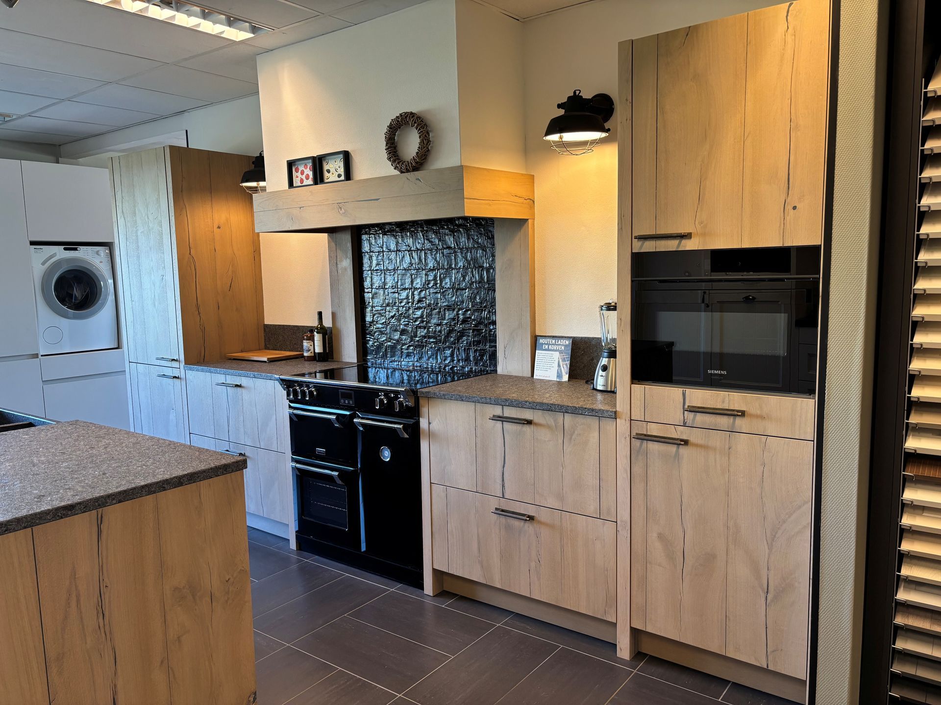 Moderne keuken met houten kasten, zwarte apparaten en granieten aanrechtbladen.