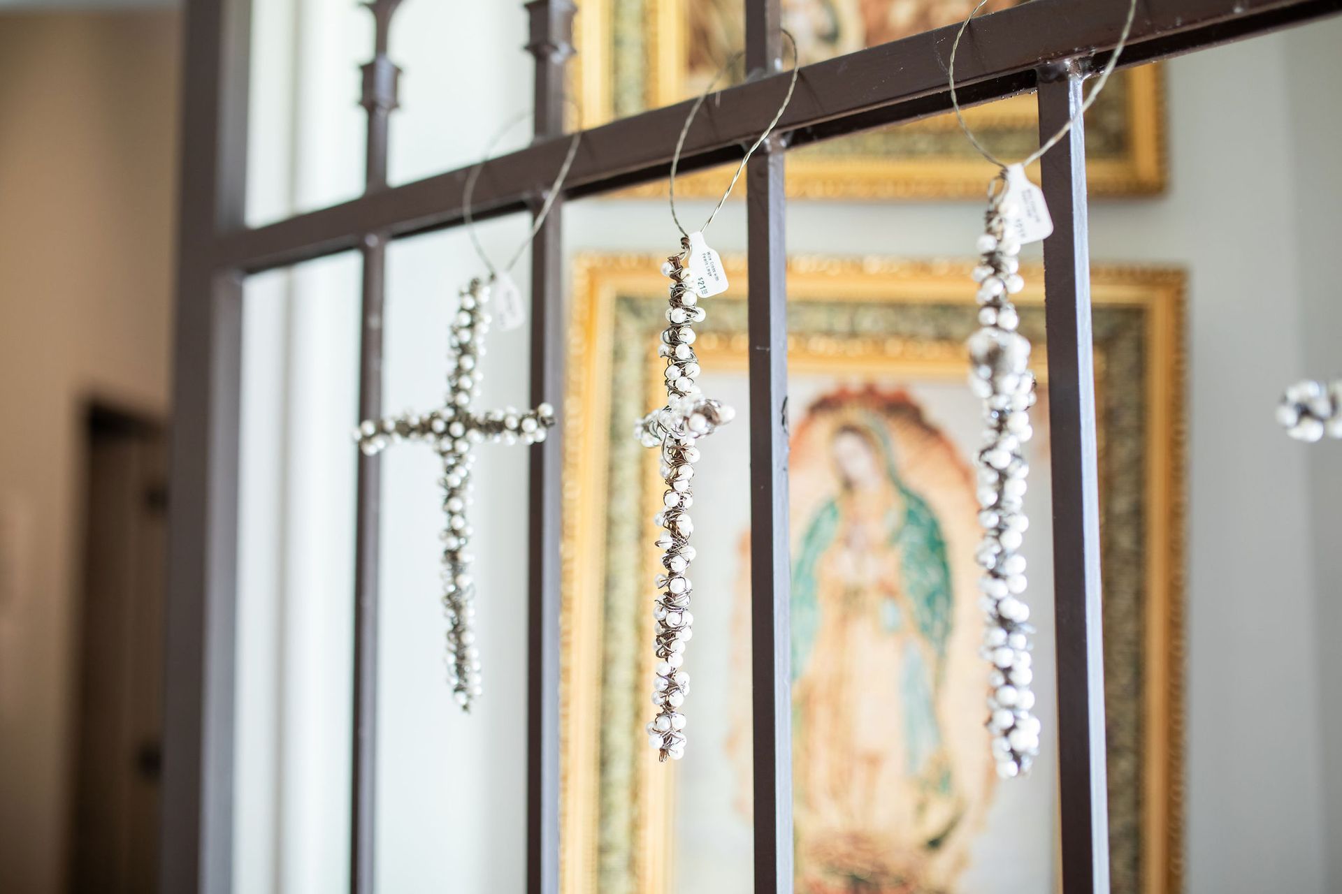 Crystals shaped into crosses and hanging in front of a framed religious painting.