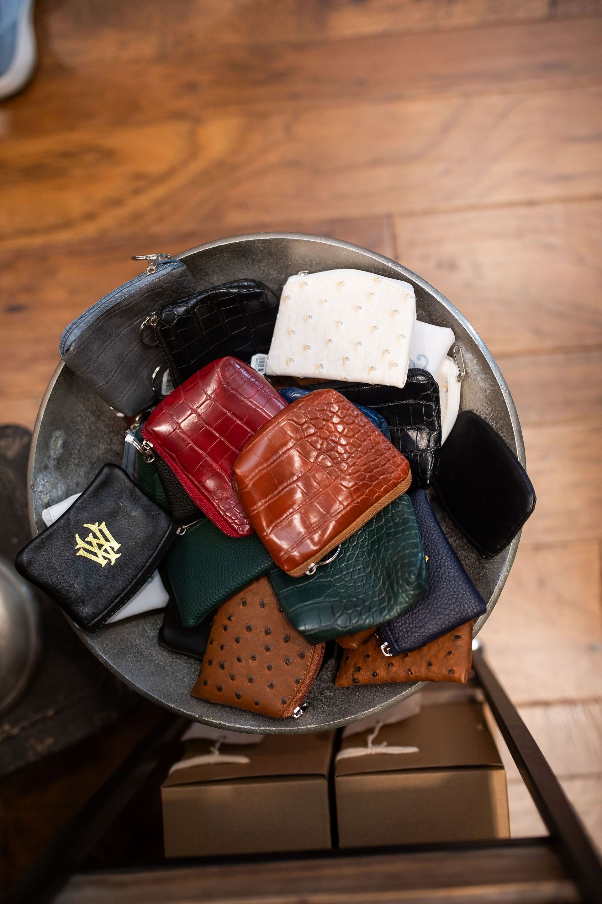 A bowl overflowing with small, colorful leather wallets on display in a shop.