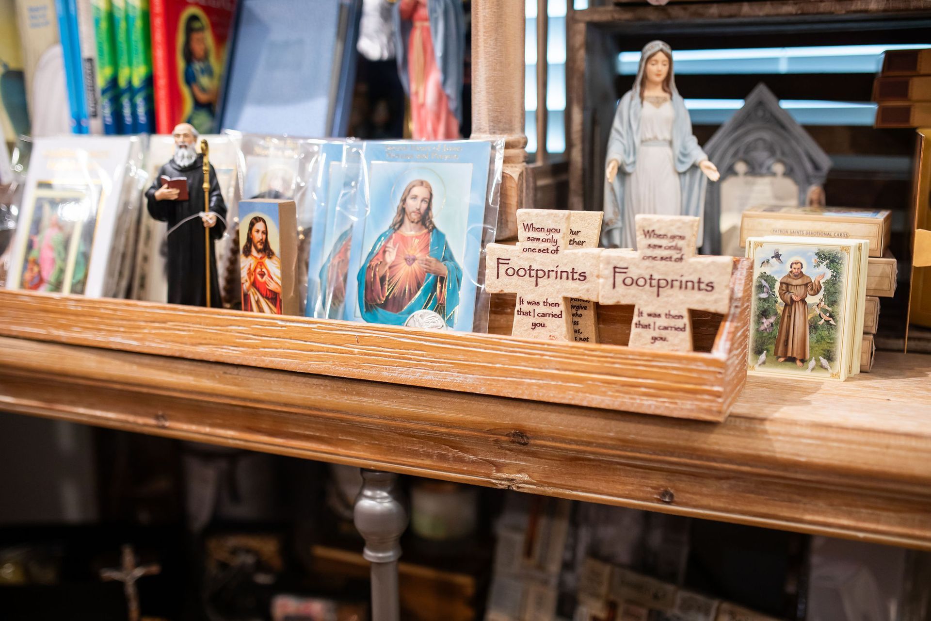 Religious items on a wooden shelf: statues, cards, and a 