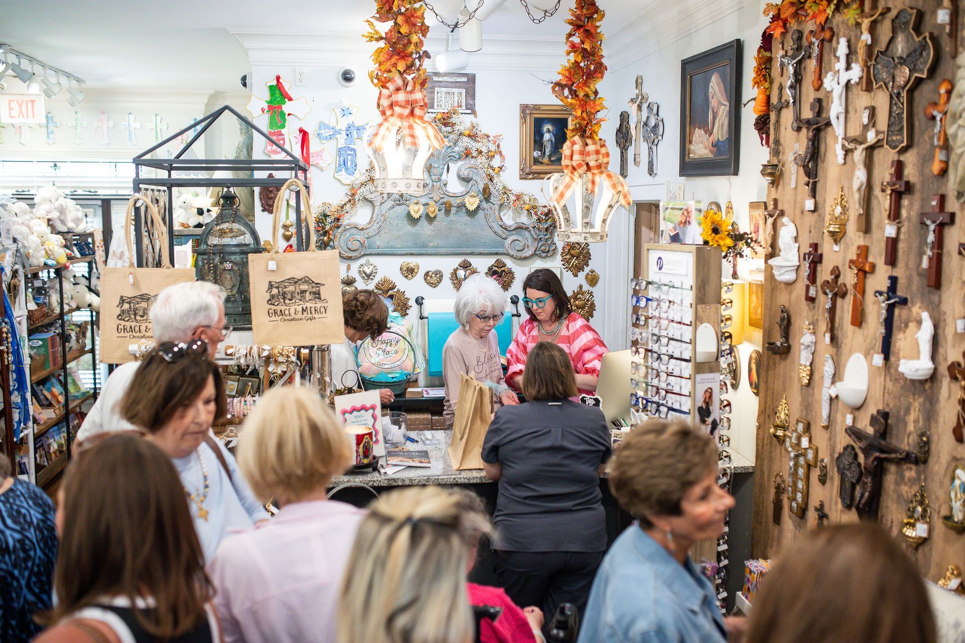 People browsing and shopping inside a religious items store, filled with crosses and other items.