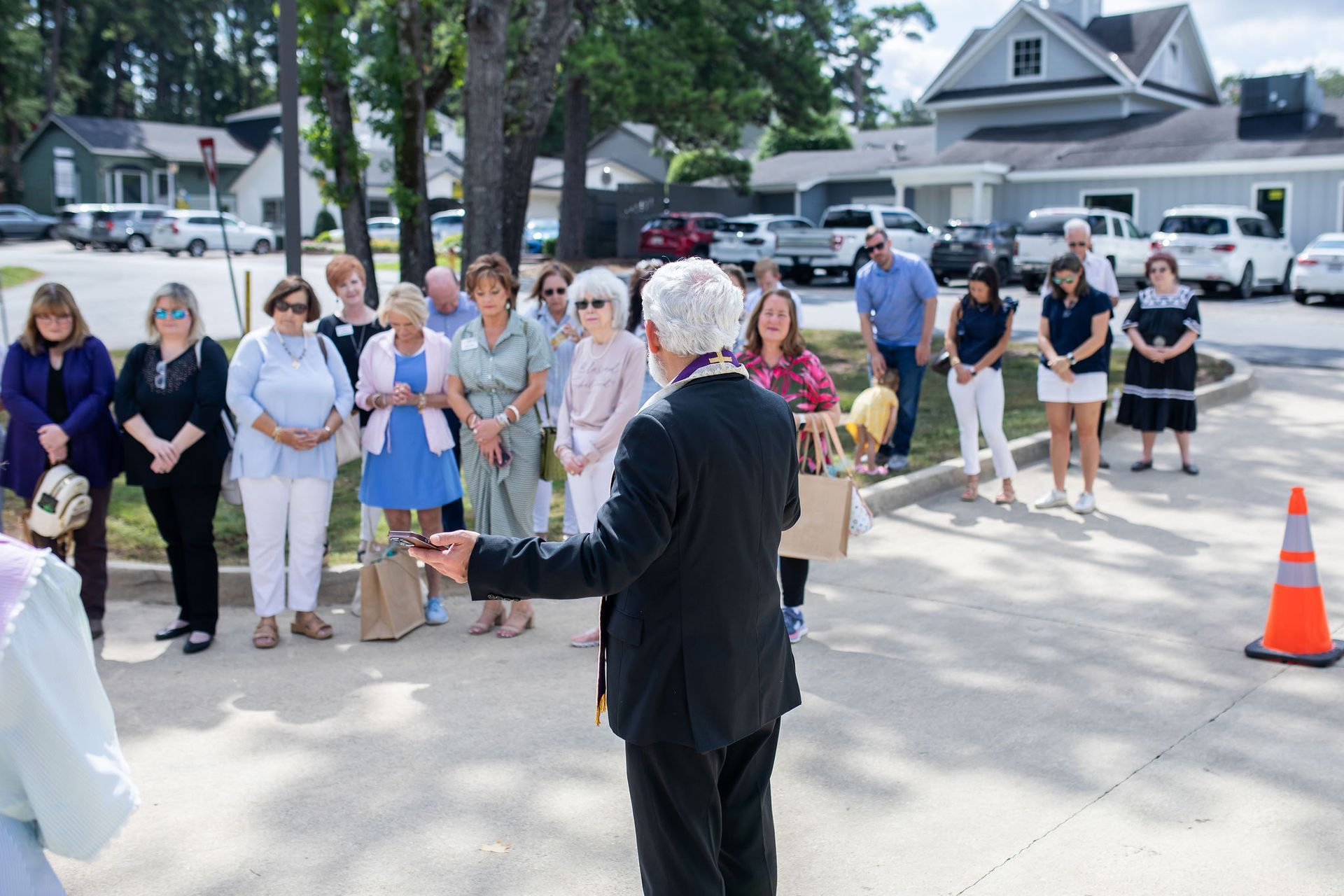 A man in a suit speaks to a group of people outside a building.