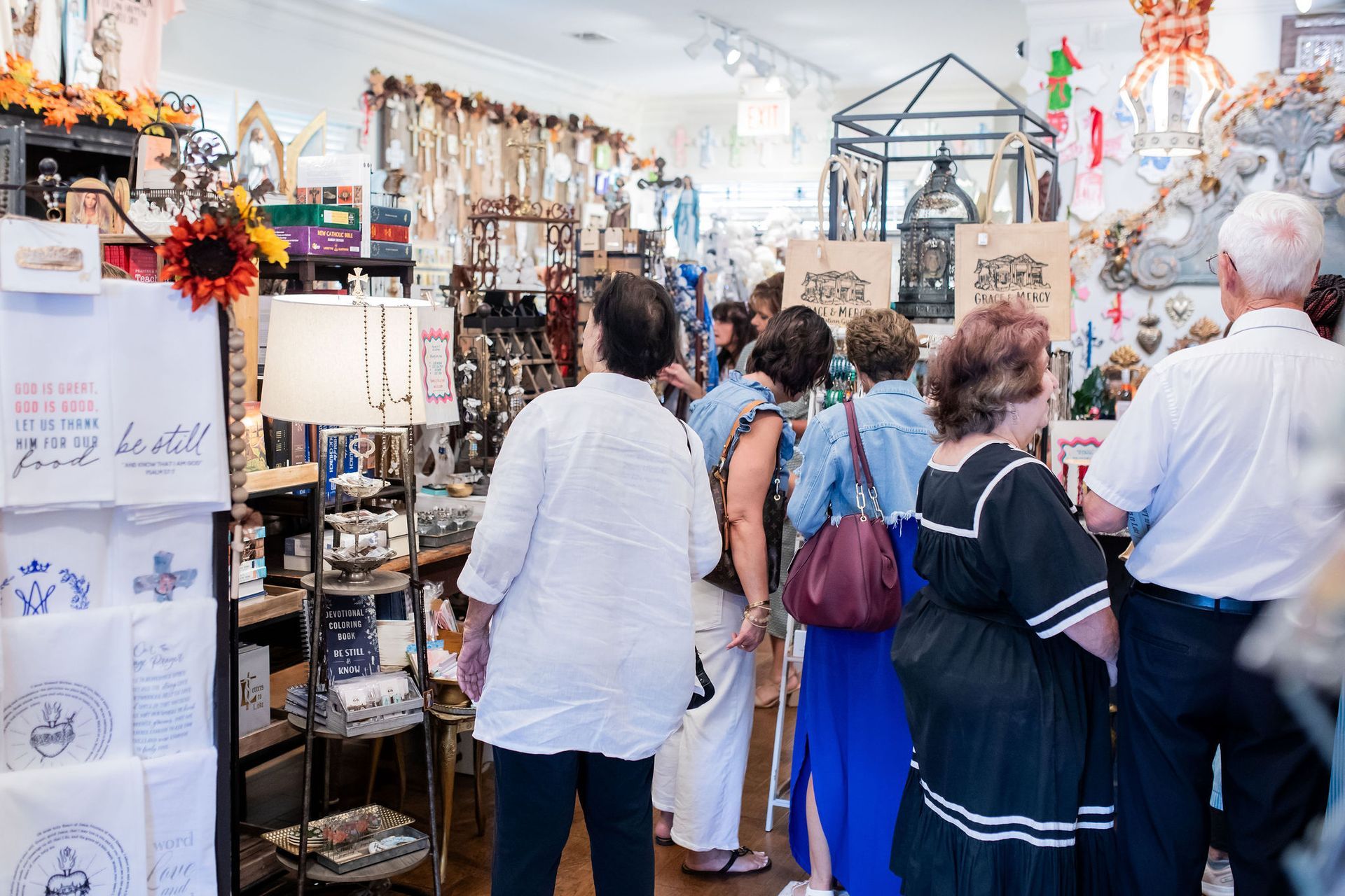 People browsing merchandise in a brightly lit retail shop, with various decorative items on display.