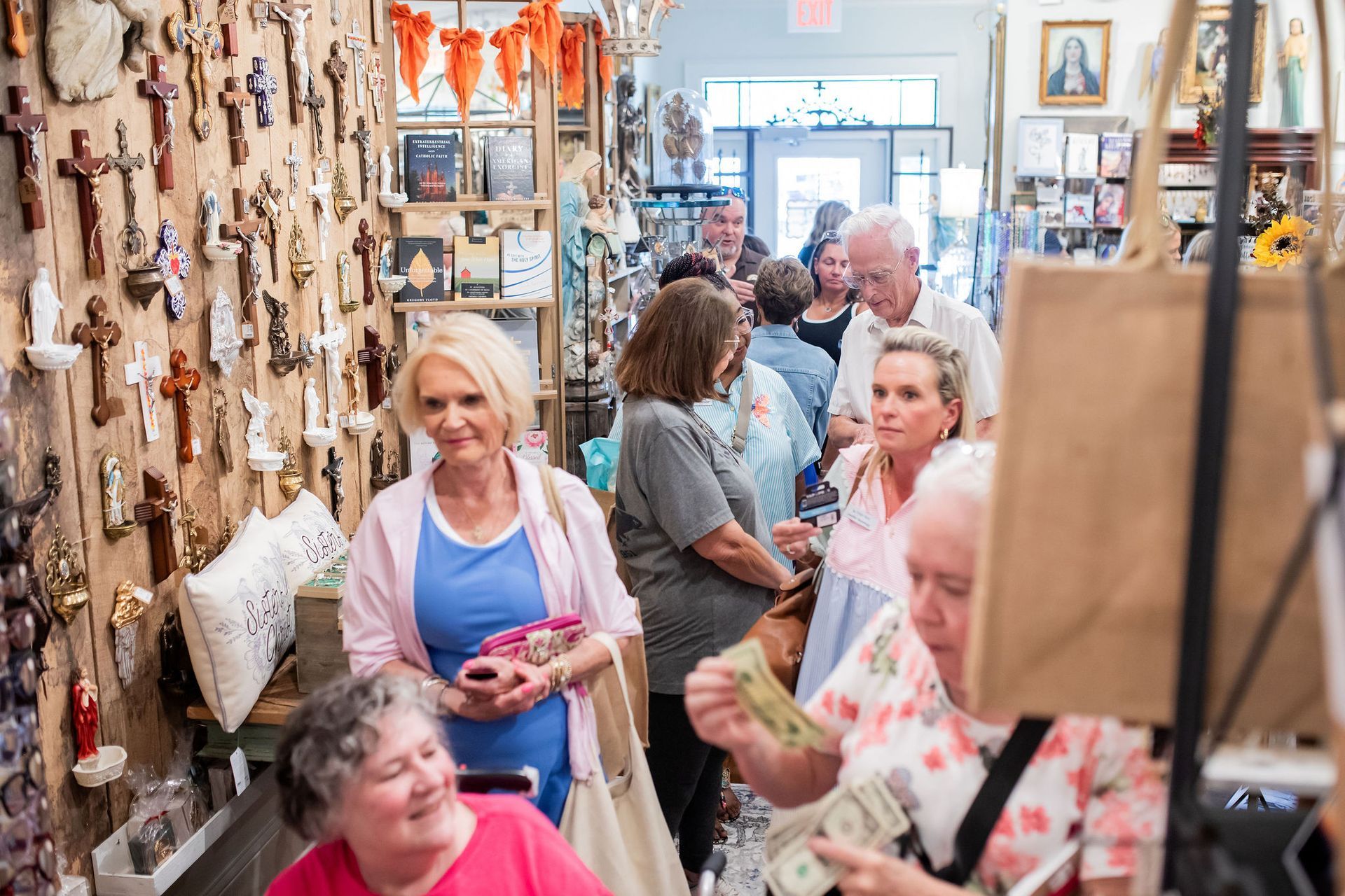 People browse a shop filled with religious items; some look at crosses on a wall.