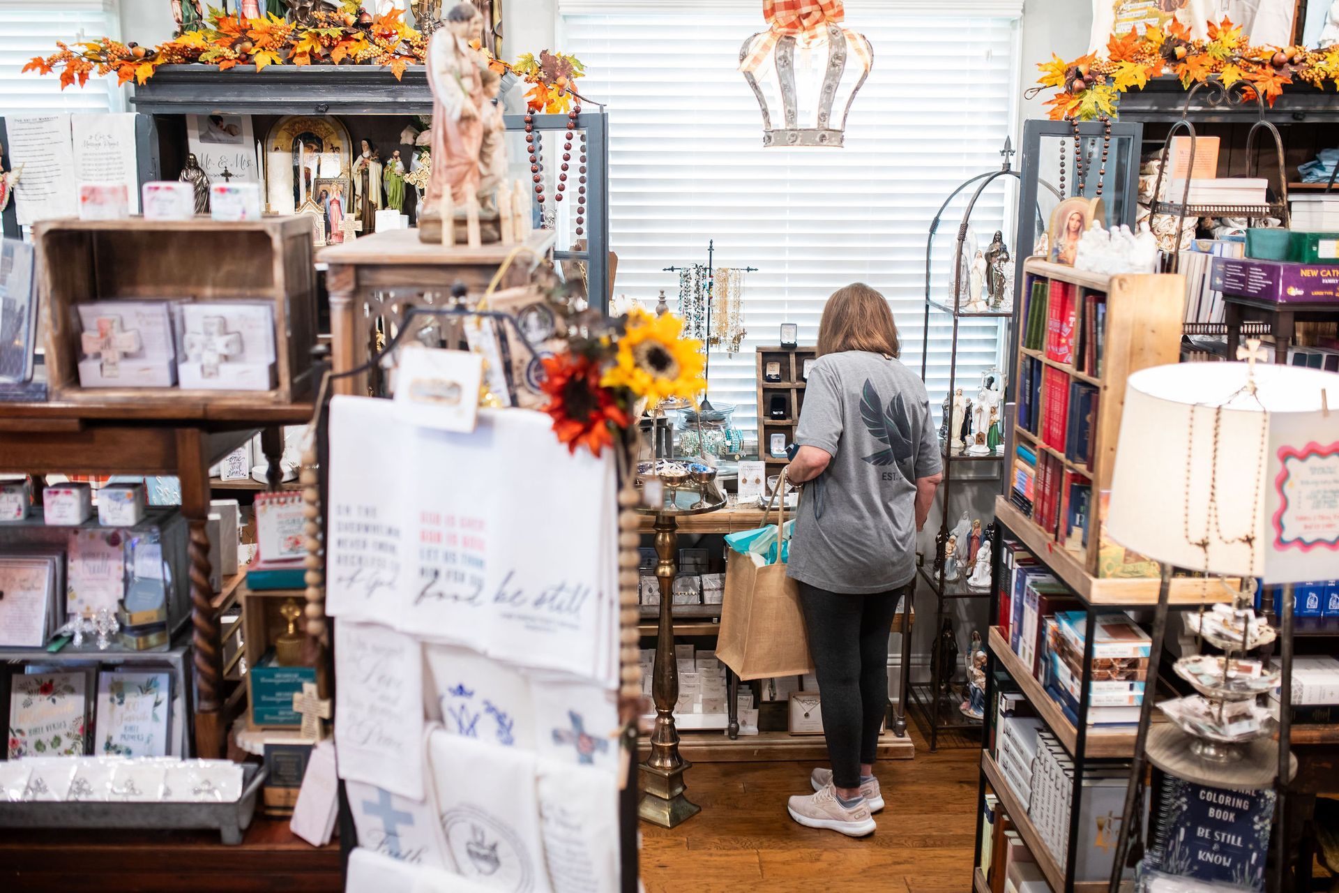 Woman browsing items in a cluttered gift shop filled with decor and cards.