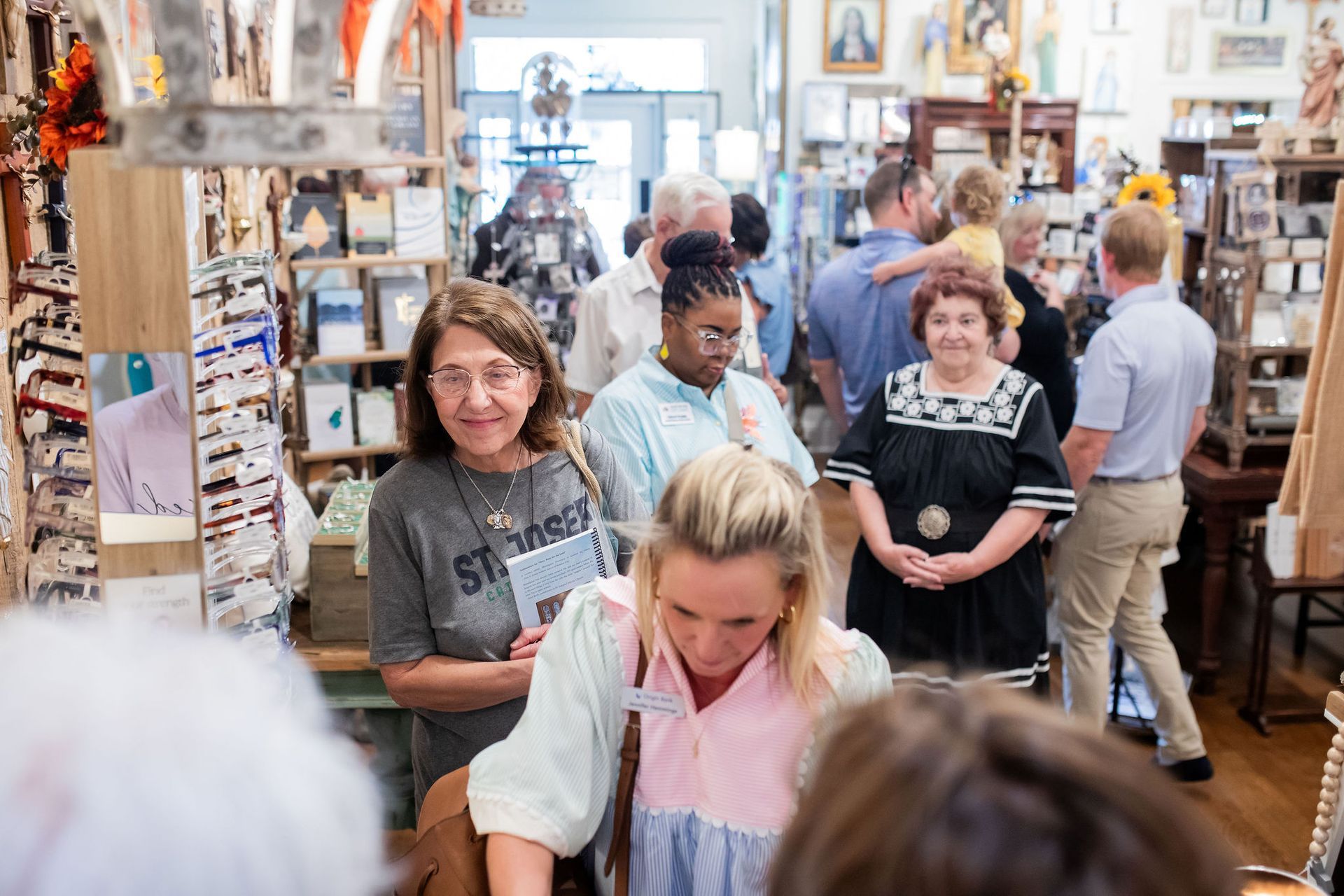 People browsing inside a crowded shop. Shelves with items line walls. Several people are smiling.