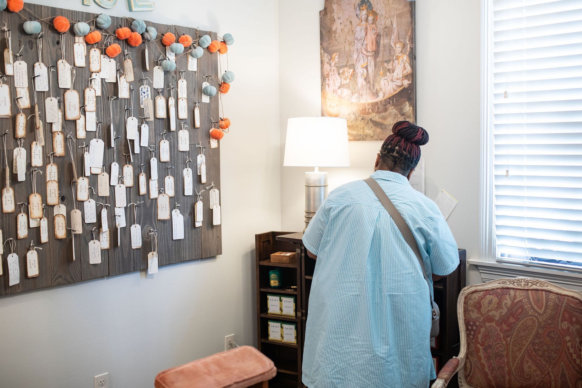 Person looking at items in a corner, featuring a tag display and a lamp.
