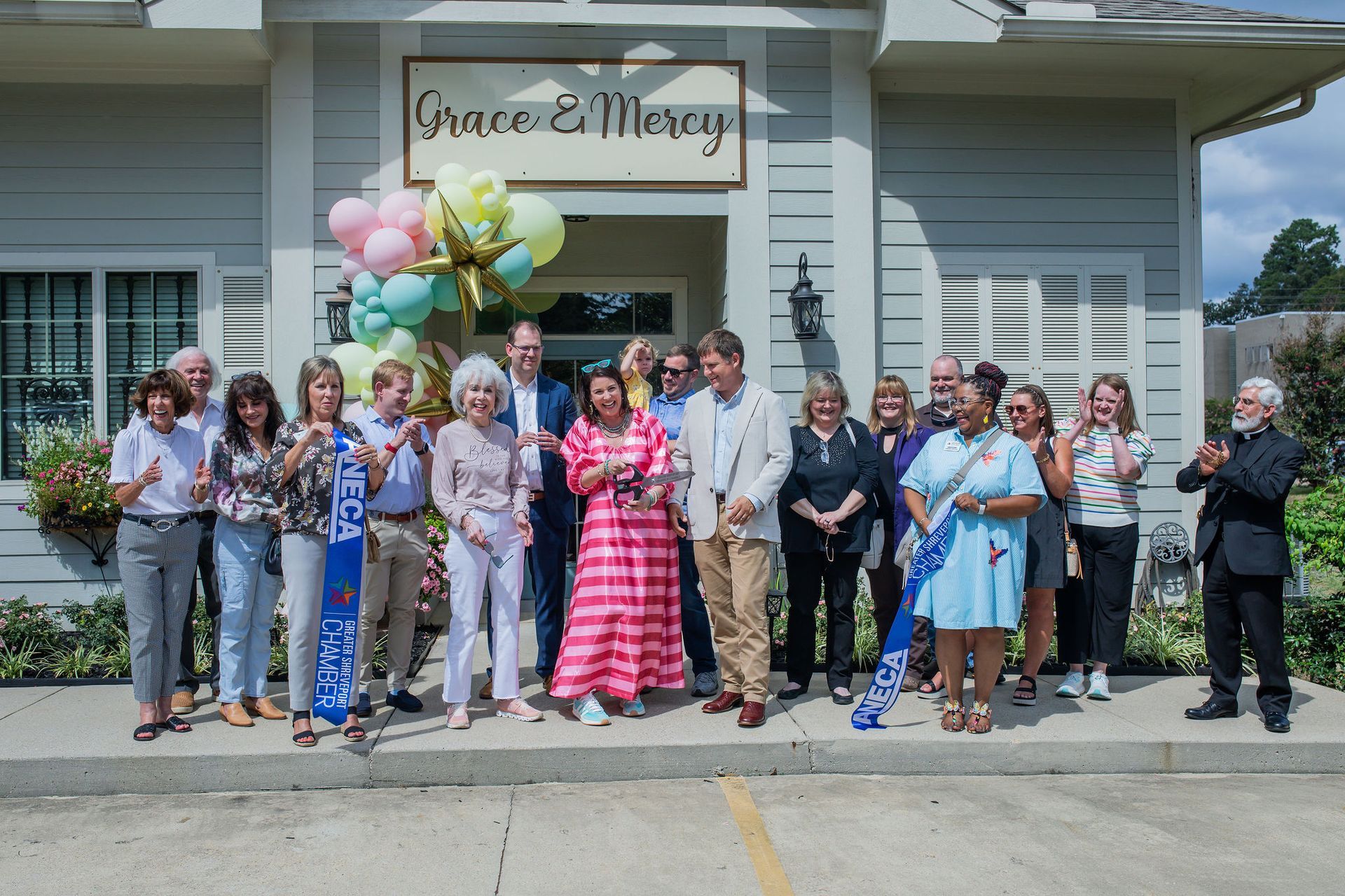 Group of people celebrating a ribbon-cutting in front of a building called 