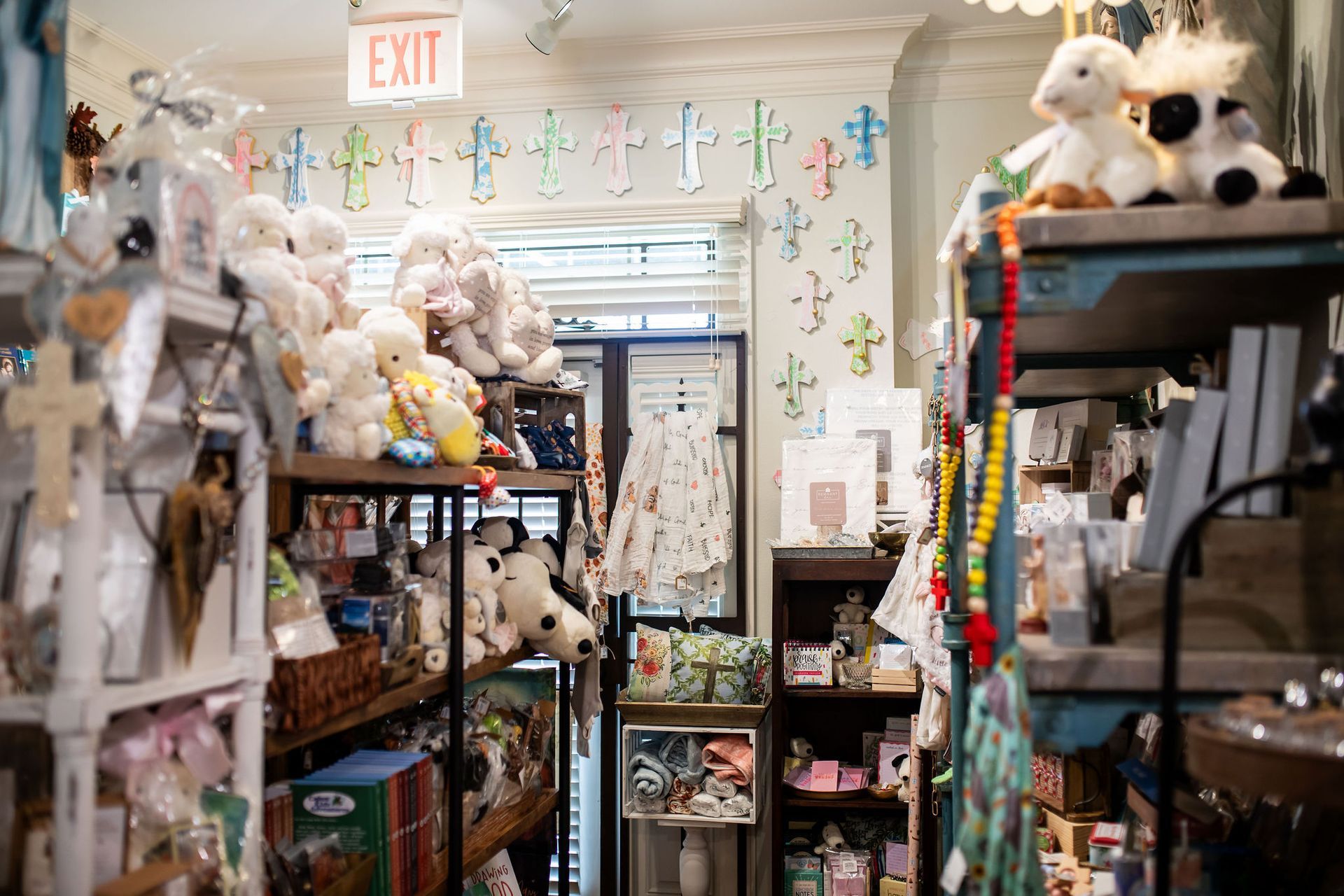 Inside a small shop: shelves of merchandise, stuffed animals, floral wallpaper, and an exit sign.