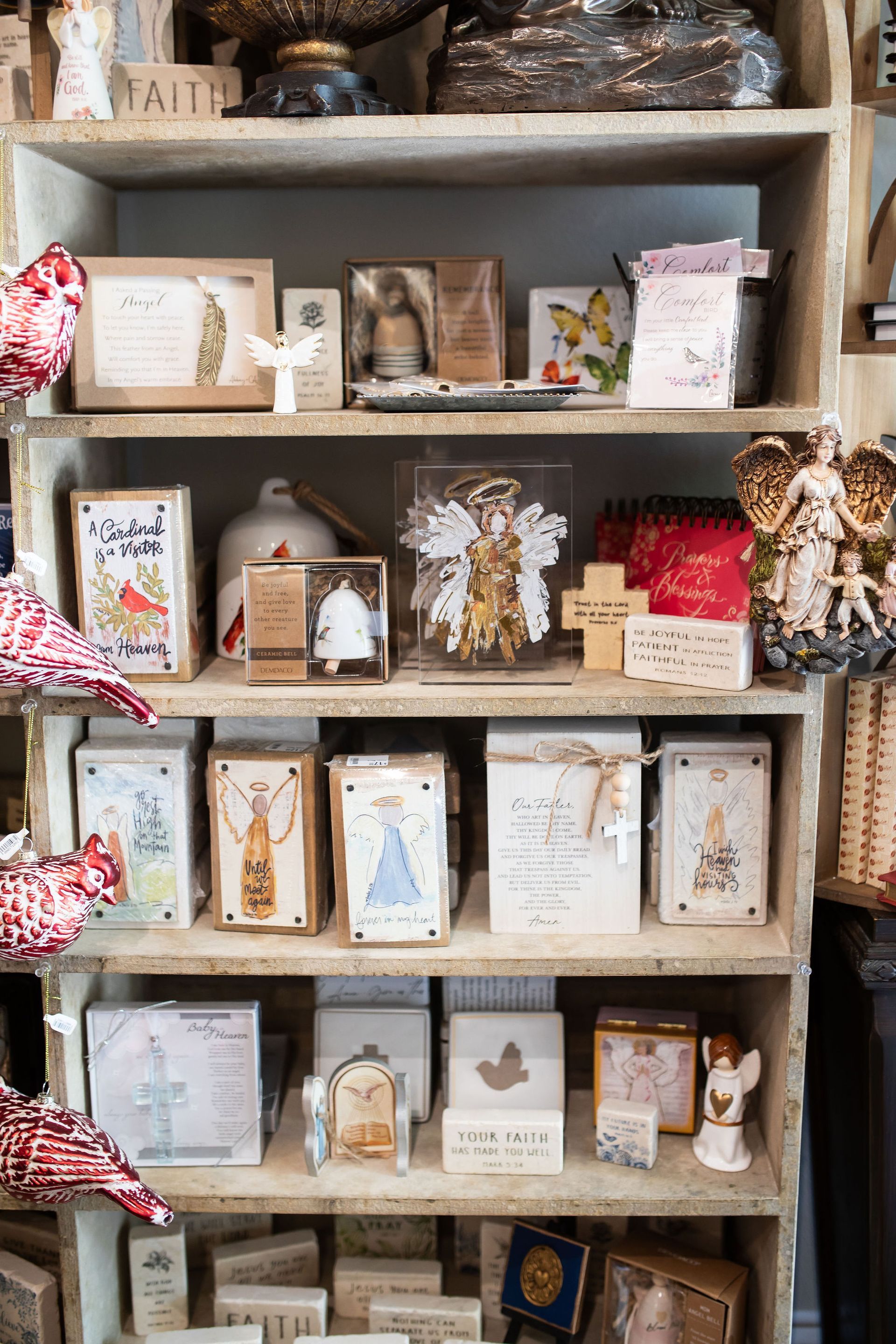 Wooden shelves filled with religious-themed gifts and cards. Neutral tones and various textures, in a shop setting.