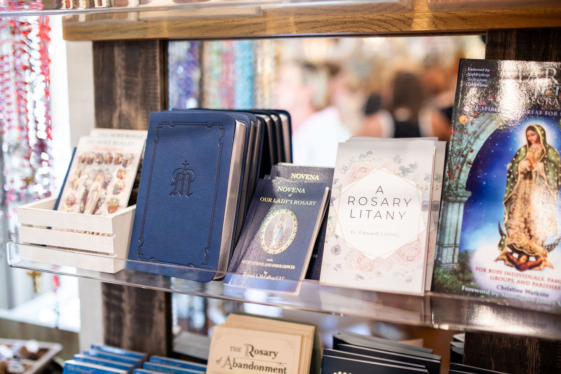 Books and religious items on a wooden shelf in a shop.