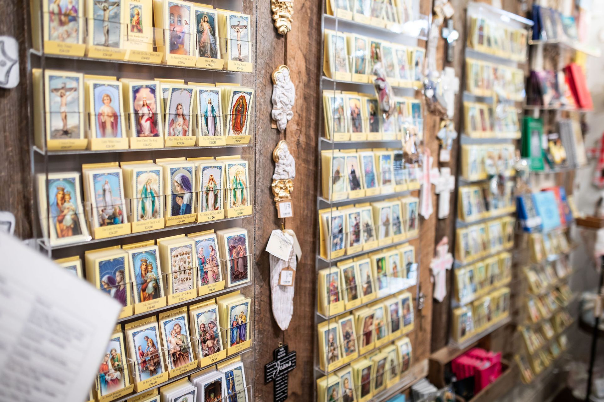Shelves displaying religious cards and items in a shop, mostly in beige and gold tones.