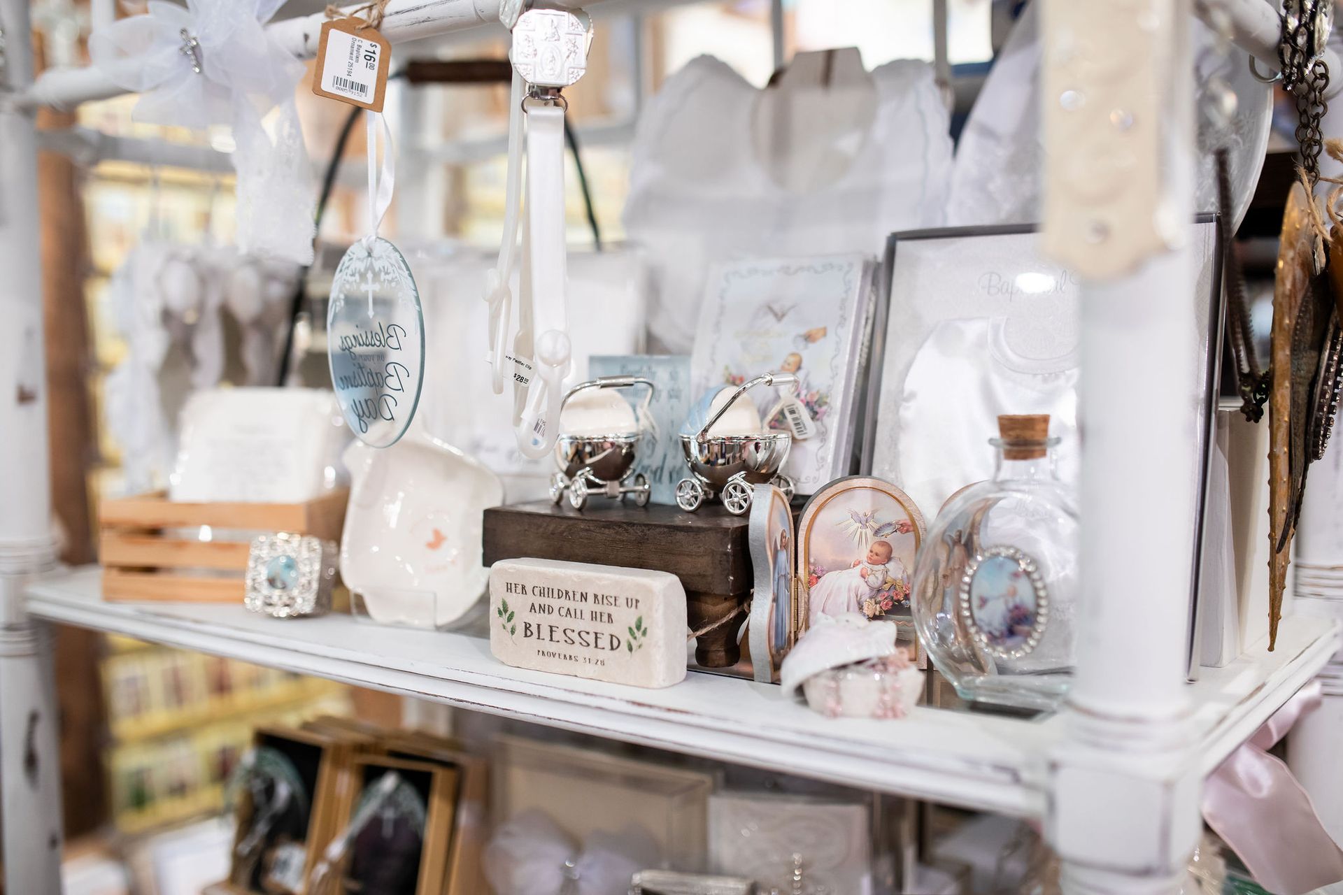 White shop shelf displaying various decorative items, including glass bottles, framed art, and trinkets.