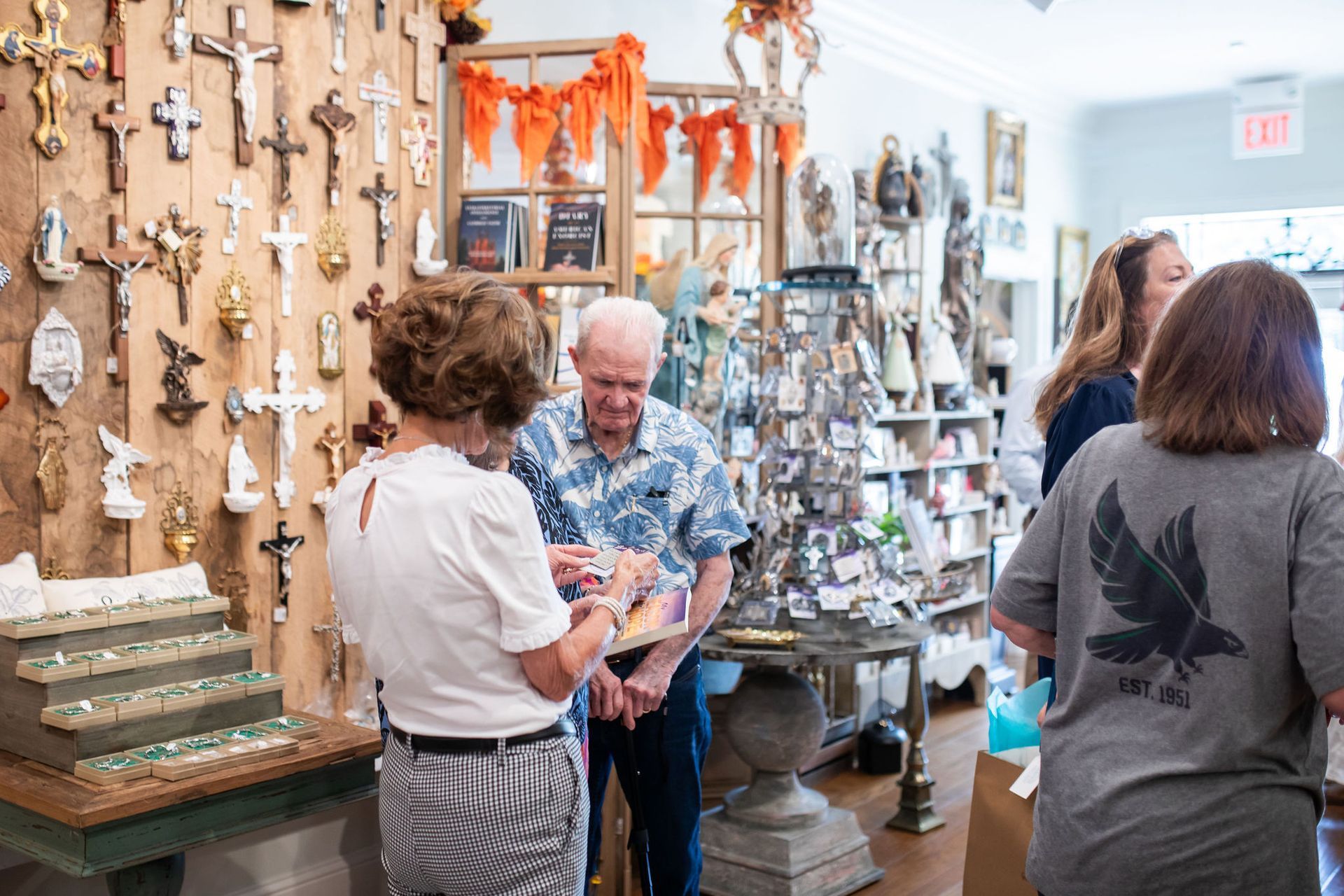 People browsing items in a shop, with a wall of crosses in the background.