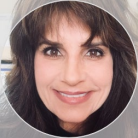 Smiling woman with brown hair and eyes, round frame.