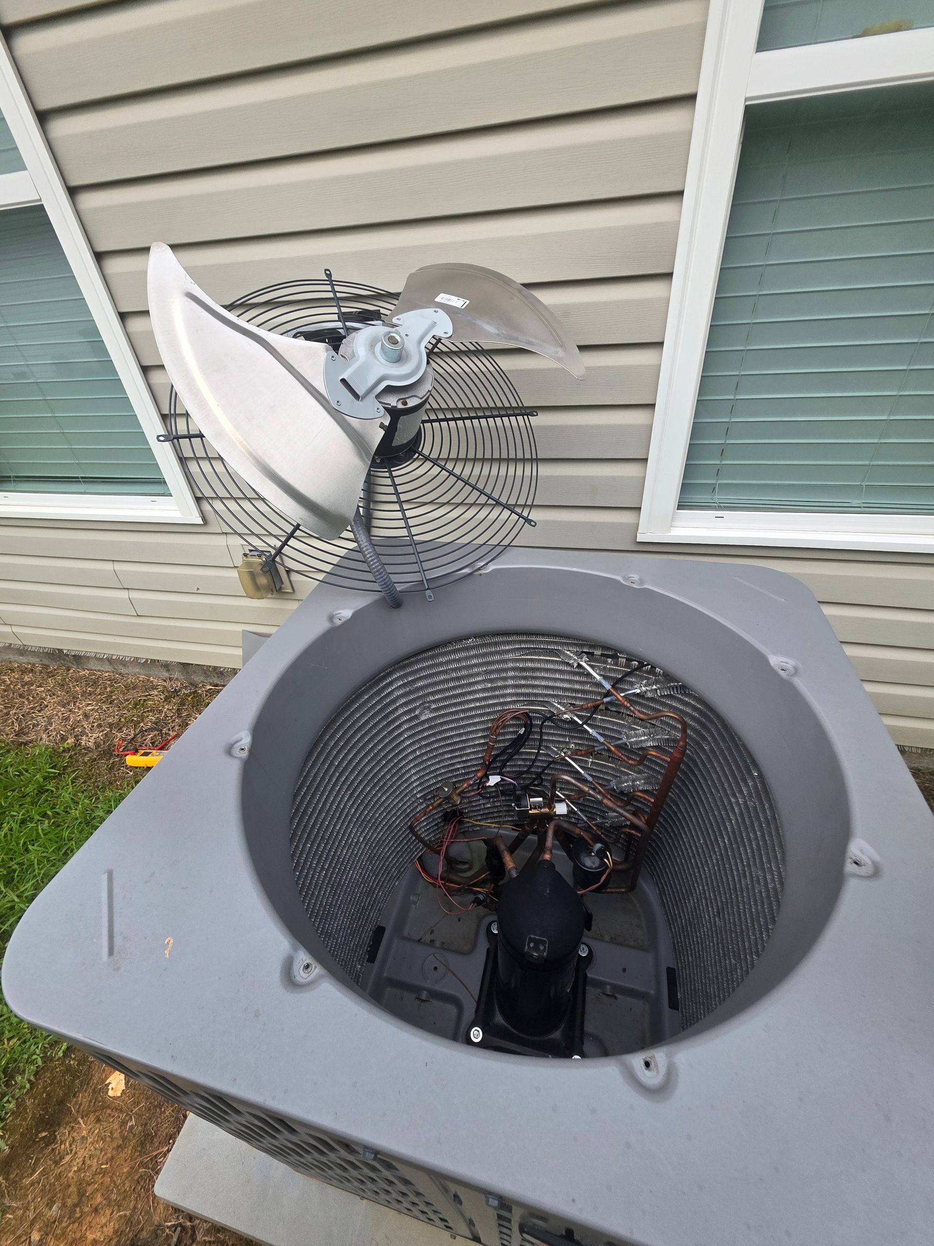 A person wearing blue gloves is cleaning an air conditioner.