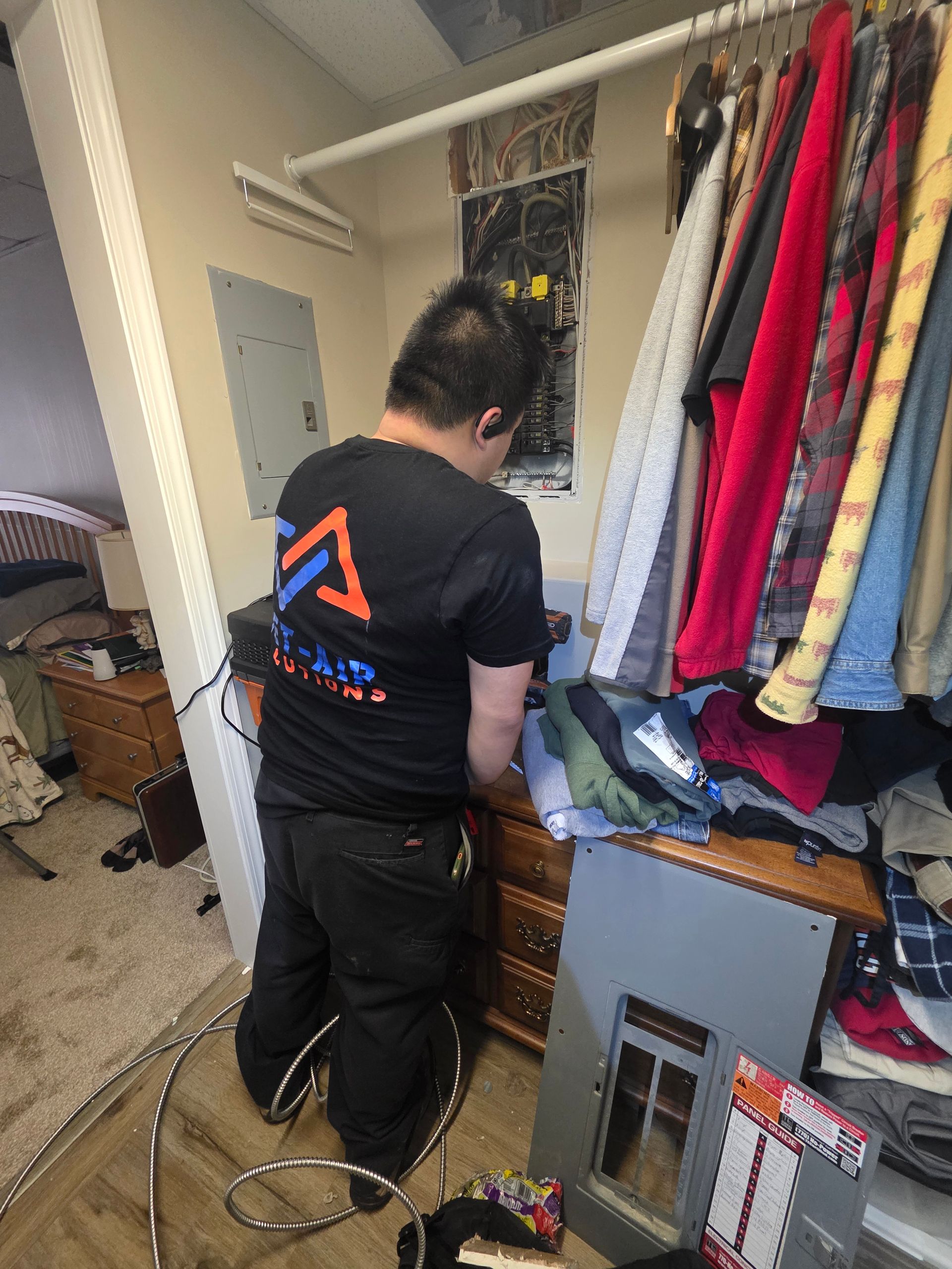A man is standing on a ladder fixing an air filter in a room.