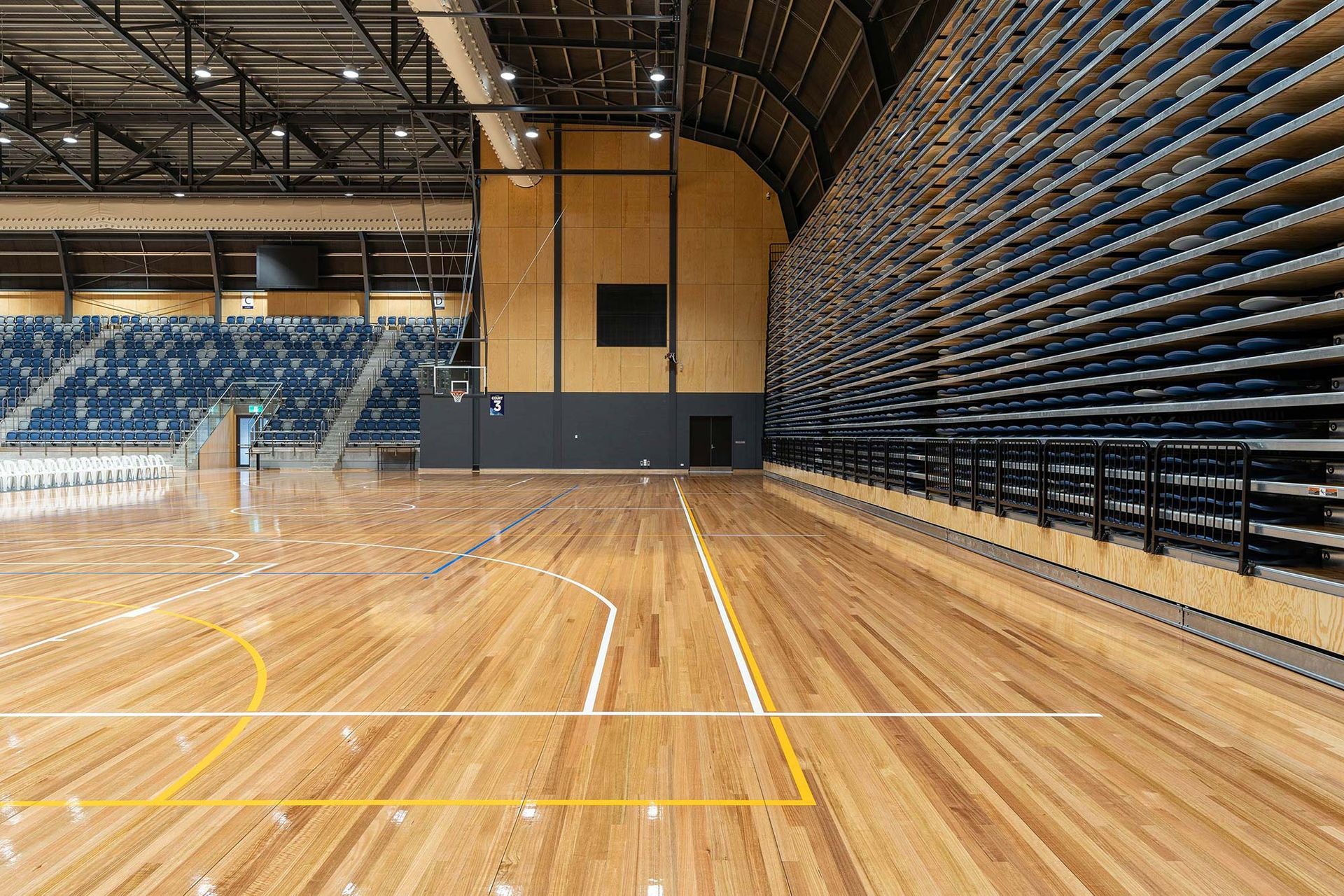 An empty basketball court with a wooden floor and bleachers.