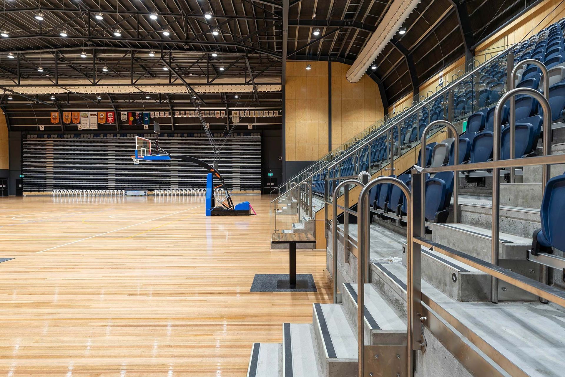 There are stairs leading up to the bleachers in a basketball court.