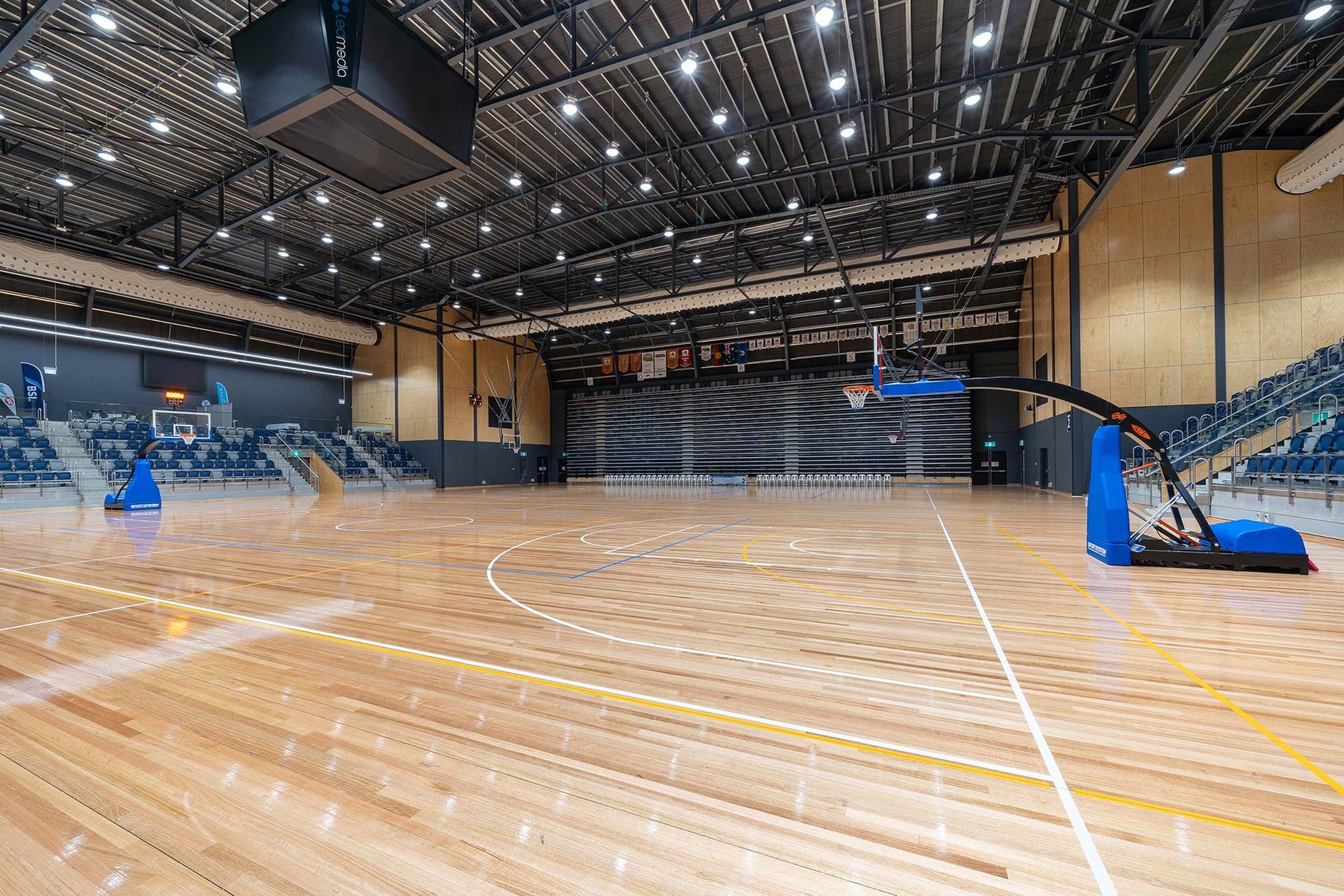 An empty basketball court in a large building with a basketball hoop.