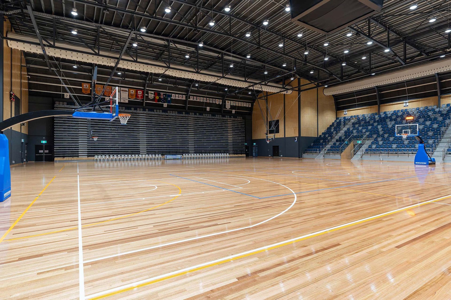 A large indoor basketball court with a wooden floor and a basketball hoop.