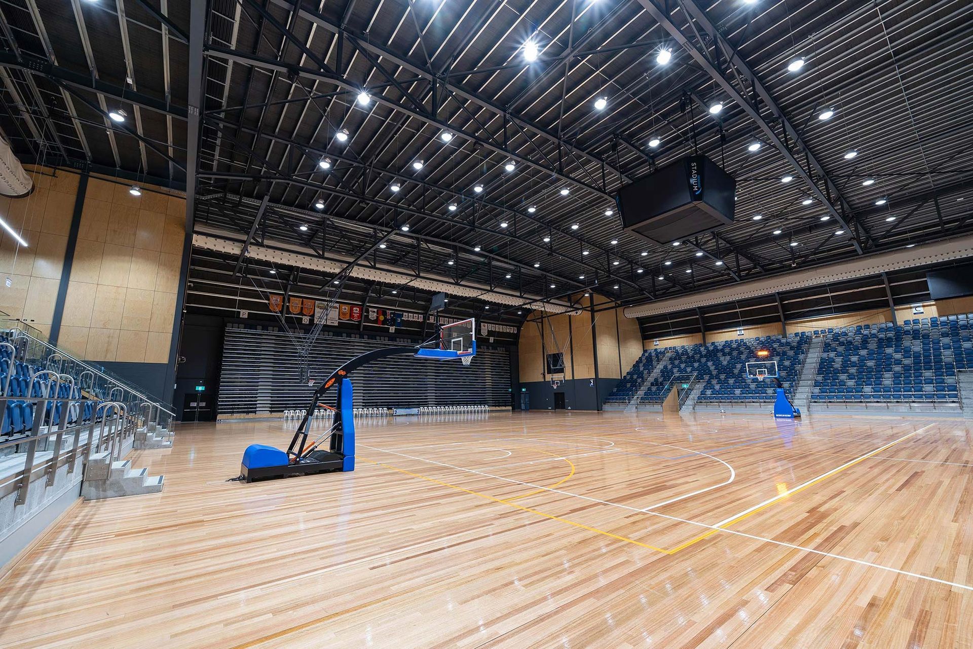A large indoor basketball court with a wooden floor and bleachers.