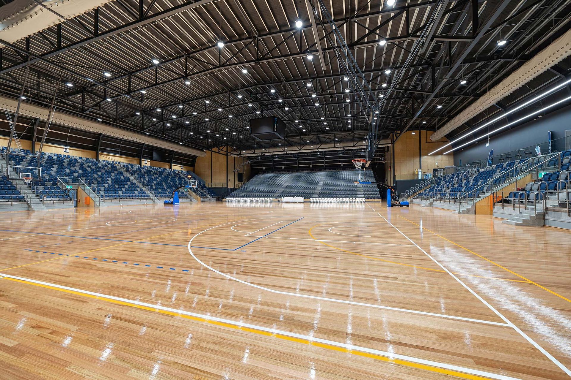 A large indoor basketball court with a wooden floor and bleachers.