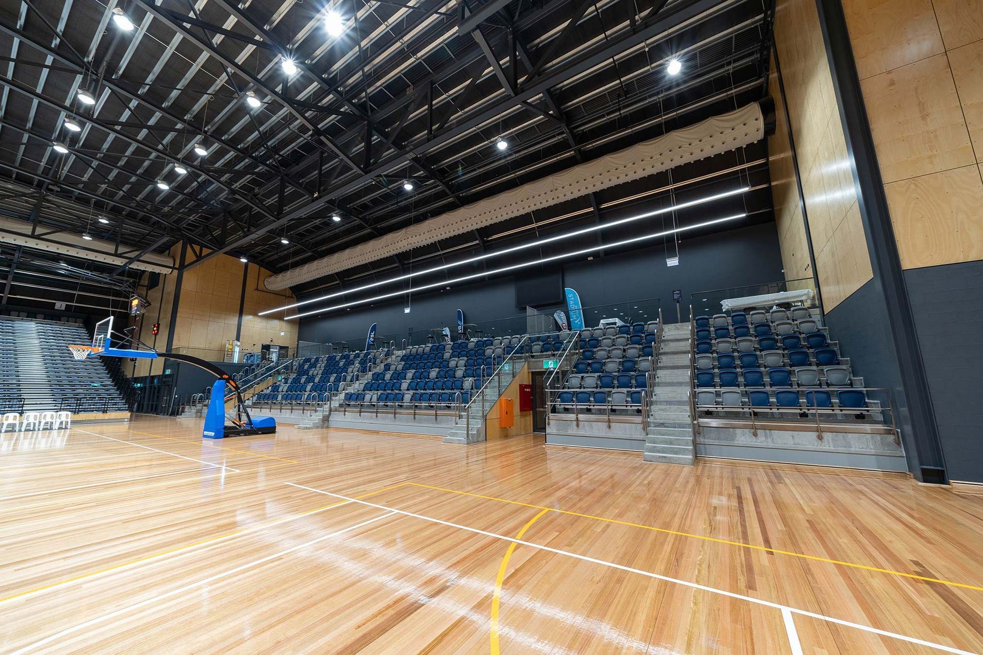 A large indoor basketball court with wooden floors and bleachers.