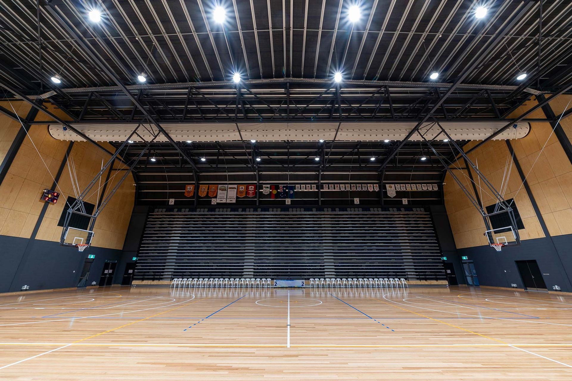 A large indoor basketball court with a wooden floor and a basketball hoop.