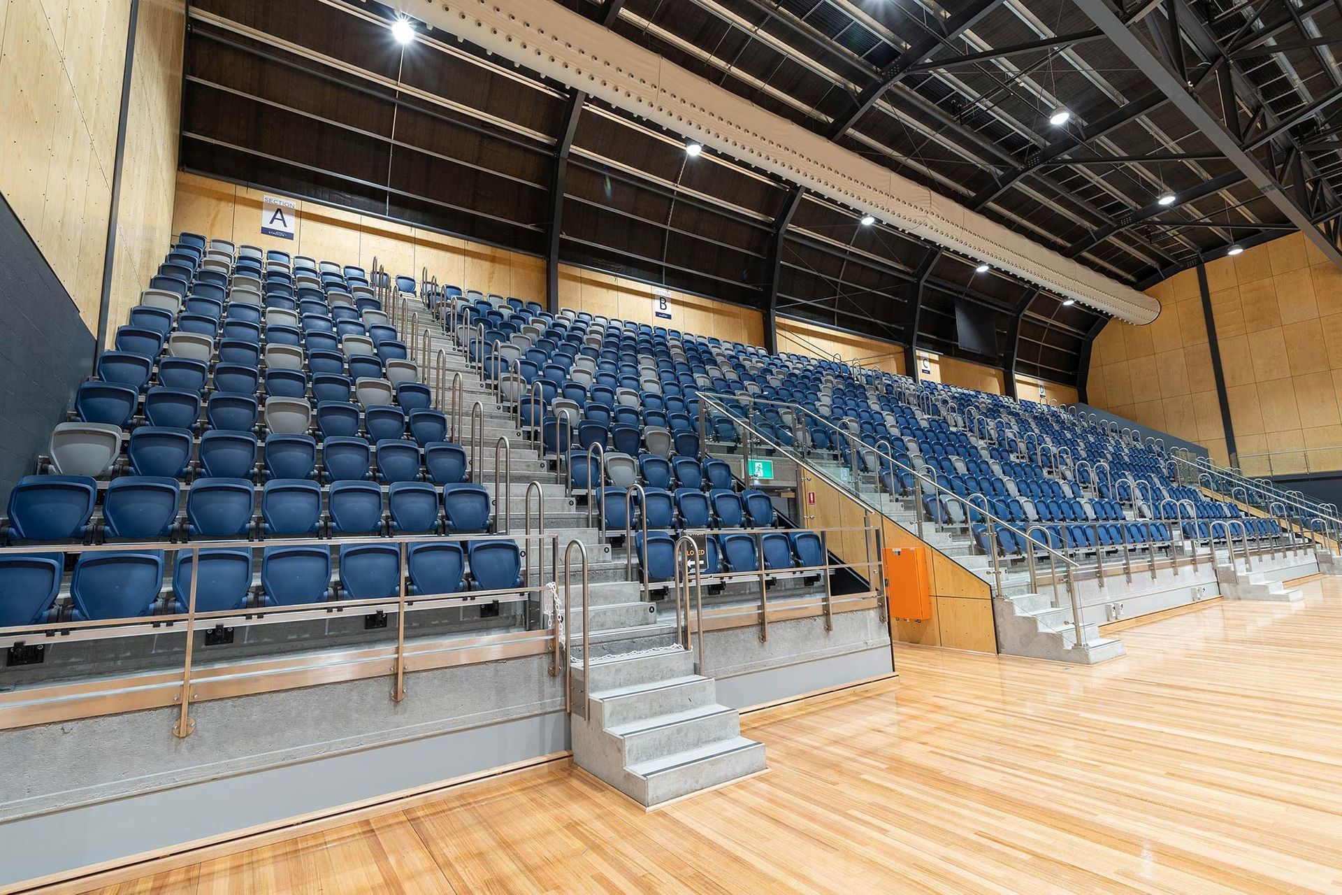A large auditorium with blue seats and wooden floors.