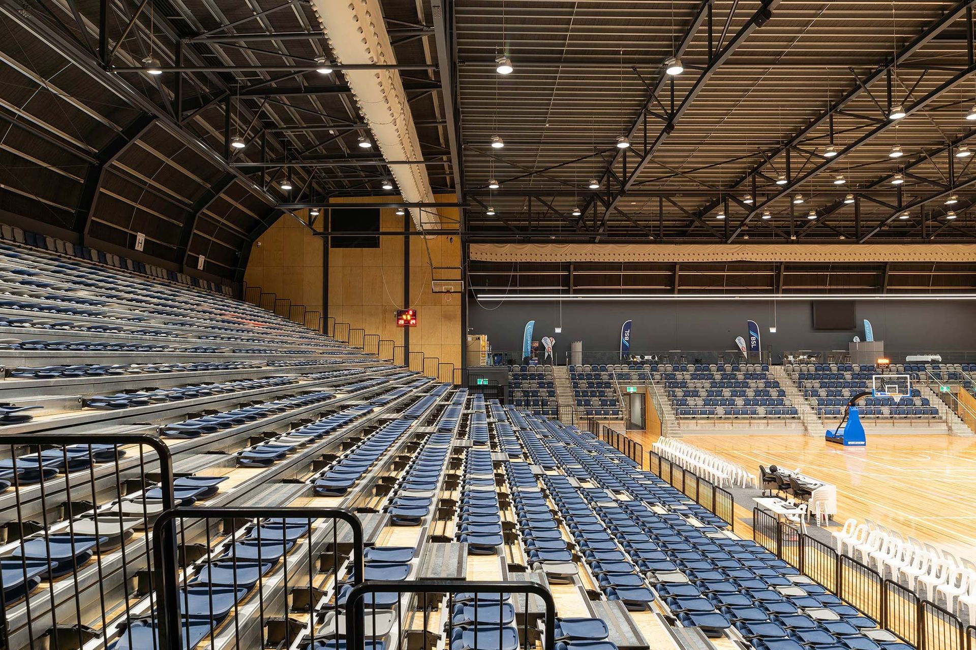 A large empty stadium with rows of blue seats.
