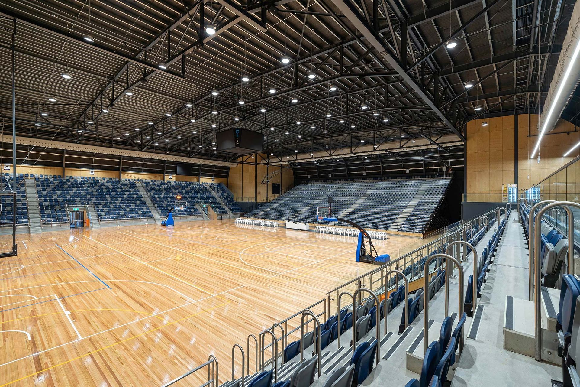 A large indoor basketball court with bleachers and a wooden floor.